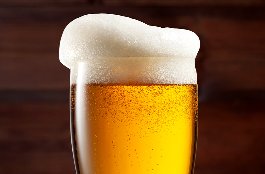 Golden beer in a tall glass with a thick white foamy head.